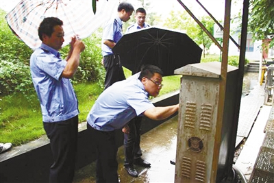 环保部门工作人员正冒雨检查污水处理厂